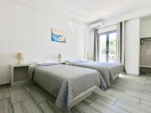 two beds in a white room with a window at Anny Studios & Rooms Perissa Beach in Perissa +55 photos