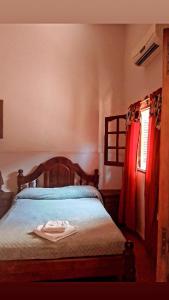 a bedroom with a bed with a wooden headboard and a window at Hostal Las Carretas in San Miguel de Tucumán