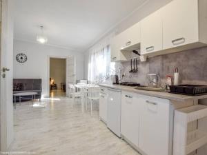 a kitchen with white cabinets and a dining room at Domki pod Dębami in Mojęcice