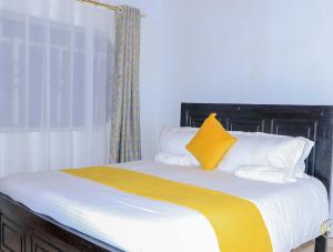 1 cama con manta amarilla y almohadas blancas en Perfection, en Meru