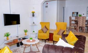 ein Wohnzimmer mit gelben Stühlen und einem Sofa in der Unterkunft Perfection in Meru