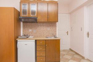 a kitchen with wooden cabinets and a white refrigerator at Welcome Naxos in Agios Prokopios