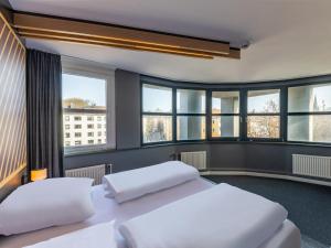 two beds in a room with windows at B&B HOTEL Aachen City-Ost in Aachen