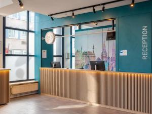 an office with a blue wall and a reception desk at B&B HOTEL Aachen City-Ost in Aachen