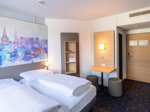 a hotel room with two beds and a desk at B&B HOTEL Aachen City-Ost in Aachen