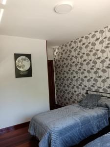 a bedroom with a bed and a wall at Casa Ruliña in Lalín