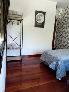 1 dormitorio con 1 cama en una habitación con suelo de madera en Casa Ruliña, en Lalín