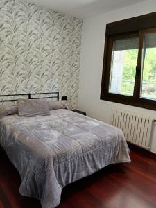 1 dormitorio con cama, ventana y pared en Casa Ruliña en Lalín