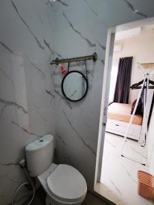 a bathroom with a toilet and a mirror and a bed at LOBLUS (Low Budget Luxury Stay) in Padang