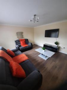 a living room with two couches and a flat screen tv at Cozy 4-bed House in Walmley in Birmingham