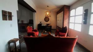 Una sala de estar con sillas rojas y un sofá. en Casa amplia y confortable, totalmente amoblada, quincho con asador, excelente ubicación, en Santiago del Estero