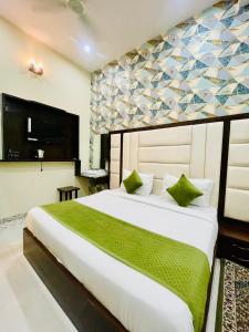 ein Schlafzimmer mit einem großen weißen Bett mit grünen Kissen in der Unterkunft Hotel Aspiration in Tājganj