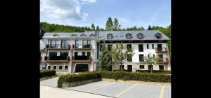 a large white building in a parking lot at JÁNOŠÍK Apartmány in Terchová