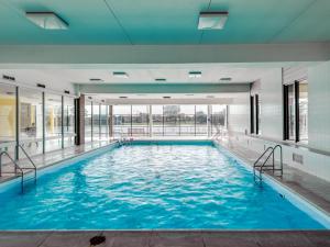 een groot zwembad met blauw water in een gebouw bij Huswell - Apartment with lake view & common indoor pool in Knokke-Heist