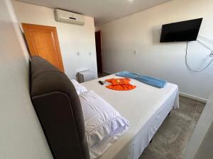 Habitación pequeña con cama, TV y cama. en Dantas Hotel, en Parauapebas