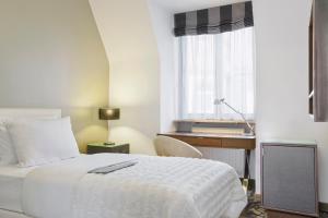 a bedroom with a bed and a desk and a window at Le Méridien Grand Hotel Nürnberg in Nuremberg