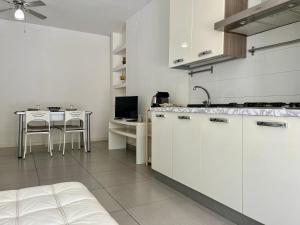 een keuken met witte kasten en een tafel. bij Flat with Terrace & Pool in Mondello