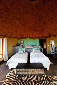 1 dormitorio con 2 camas y techo de paja en We Kebi Safari Lodge en Sesriem