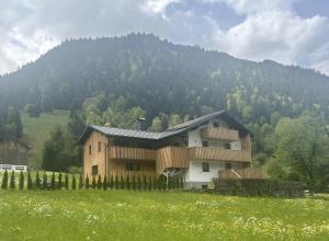 ein Haus auf einem Feld vor einem Berg in der Unterkunft Haus Lechner in Gaschurn