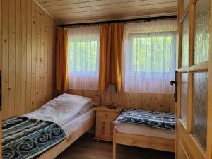 1 dormitorio con 2 camas y ventana en Domki Zacisze, Okoniny en Śliwice