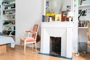 a living room with a white fireplace and a chair at Cozy studio 2 steps from the Eiffel Tower in Paris