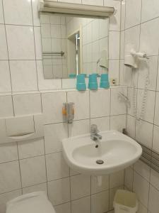 a white bathroom with a sink and a toilet at CityPark Aparthotel in Cologne