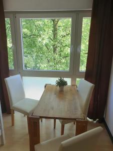 a wooden table with white chairs and a window at CityPark Aparthotel in Cologne