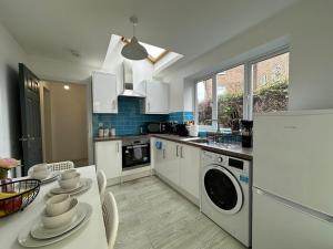 a kitchen with white appliances and a table with chairs at Comfortable Apartment Central Bedford FREE Parking & Private Garden in Bedford