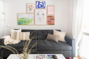 Una sala de estar con un sofá negro y algunos cuadros. en El balcón de San Antón by Clabao, en Pamplona