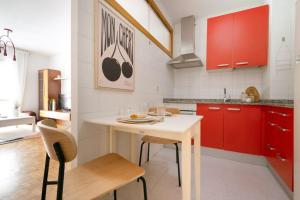 Una cocina con gabinetes rojos y una mesa y sillas blancas. en El balcón de San Antón by Clabao, en Pamplona 12 fotos más