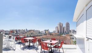 een balkon met tafels en stoelen en uitzicht op de stad bij Akeah Hotel Gran Vía in Madrid