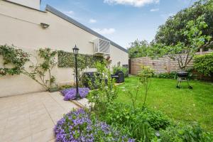 a garden with purple flowers next to a building at Les Arômes - Maison avec jardin 8 pers Paris in Maisons-Alfort