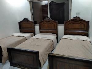 a room with three beds and a mirror at زريقات للشقق المفروشه in Irbid