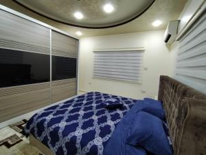 a bedroom with a bed with a blue comforter at زريقات للشقق المفروشه in Irbid