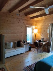 Cabanas de Melides في ميليد: غرفة نوم بجدران خشبية وأريكة ومكتب