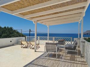 a patio with a roof with chairs and a table at Colimbos accommodation, 2 min from the beach in Áyios Nikólaos