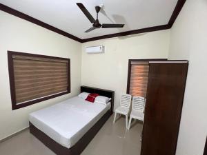 um quarto com uma cama e uma ventoinha de tecto em Fathima Apartments em Iritti