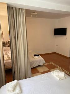 a room with two beds and a flat screen tv at Habitaciones con baño y cocina privada in Valencia
