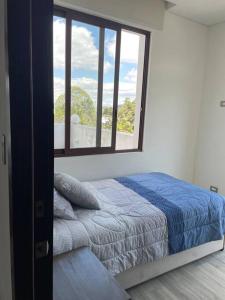 a bedroom with a bed and a large window at Cozy Apartment w Terrace Near Cayala in Guatemala