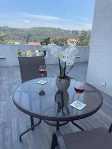 a table with two glasses of wine and a vase of flowers at Cozy Apartment w Terrace Near Cayala in Guatemala