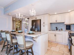 una cocina con armarios blancos y una gran isla con taburetes. en Regatta Beach Club S614, en Clearwater Beach