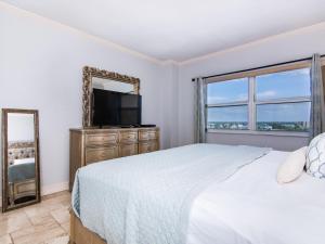 Un dormitorio con una cama, un espejo y un televisor. en Regatta Beach Club S614, en Clearwater Beach 10 fotos más