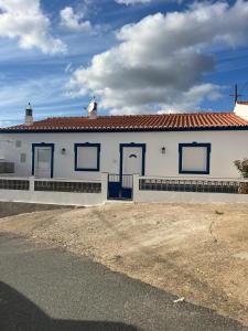 a white building with blue doors on a street at Casa dos Sapos in Mértola