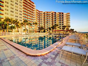 Una piscina con mesas y sillas al lado de un edificio. en Regatta Beach Club S614, en Clearwater Beach