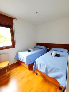 Habitación con 2 camas, mesa y ventana en Apartaments Sort Pirineus, en Sort
