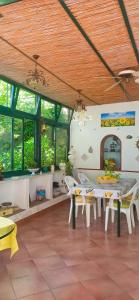 Zimmer mit einem Tisch, Stühlen und Fenstern in der Unterkunft Villa dei fiori B&B in Capri