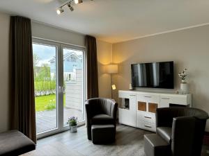 ein Wohnzimmer mit Flachbildfernseher und Stühlen in der Unterkunft Haus Nr 18, Ferienhaus Fischerhus in Wangerland