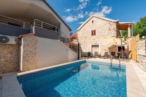 una piscina di fronte a una casa in pietra di Villa Izvor ZadarVillas a Bribir Altre 42 foto