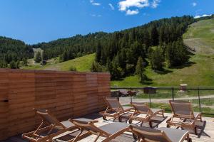 eine Gruppe von Stühlen auf einer Terrasse mit einem Berg in der Unterkunft Marmotel & Spa in Pra-Loup