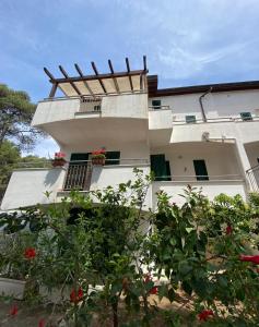 a white building with a balcony with red flowers at Villini Frutteto in Castellaneta Marina 
